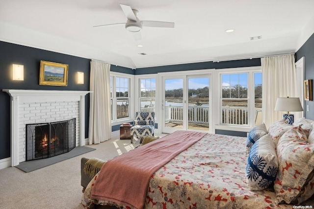 carpeted bedroom featuring ceiling fan, vaulted ceiling, access to exterior, and a brick fireplace