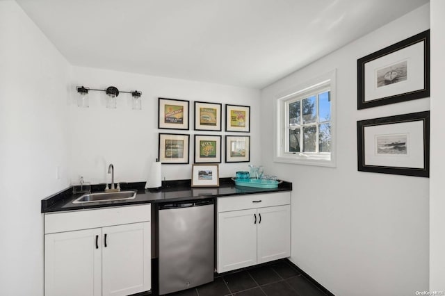 kitchen with white cabinets, dark tile patterned flooring, stainless steel dishwasher, and sink