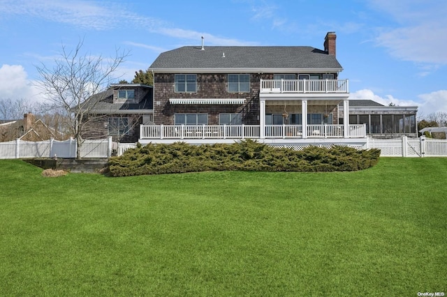 back of house with a sunroom, a balcony, and a yard