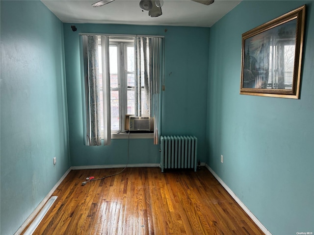 empty room with wood-type flooring, radiator, cooling unit, and ceiling fan