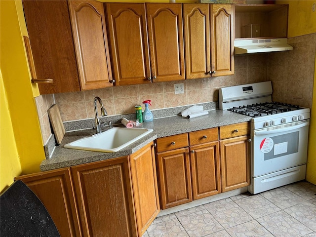 kitchen with white gas range, sink, light tile patterned floors, and tasteful backsplash