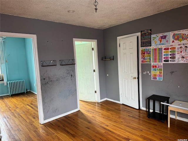 interior space with radiator heating unit, a textured ceiling, and hardwood / wood-style flooring