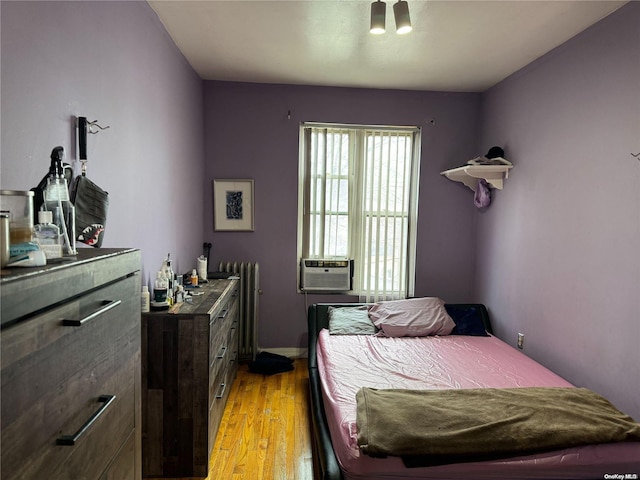 bedroom with light wood-type flooring, radiator, and cooling unit