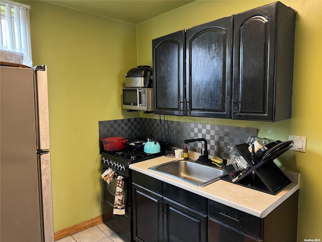 kitchen featuring appliances with stainless steel finishes, tasteful backsplash, light tile patterned floors, and sink