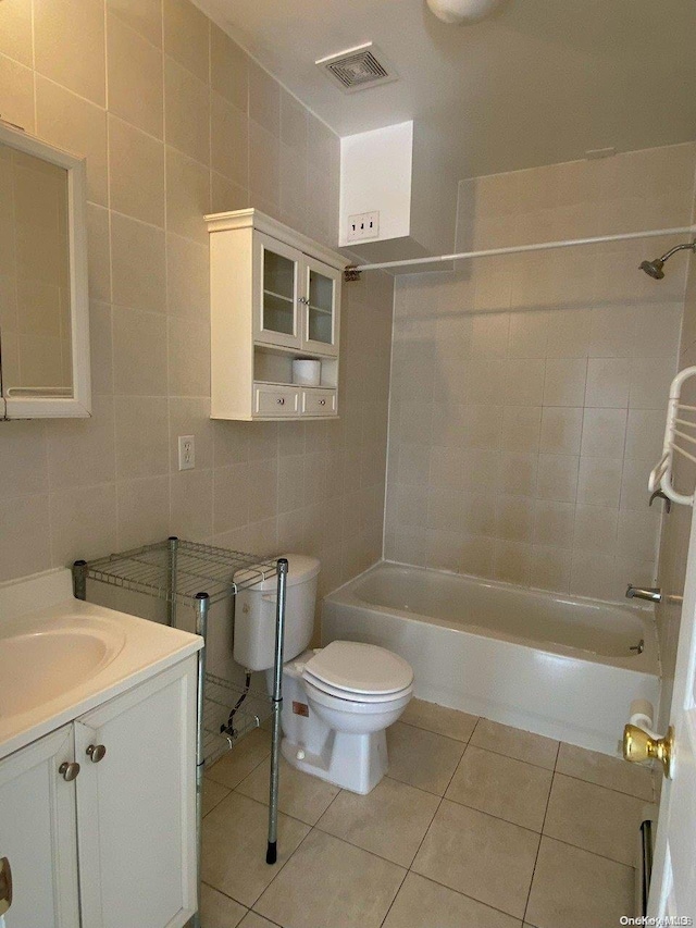 full bathroom with washtub / shower combination, tile patterned floors, toilet, vanity, and tile walls