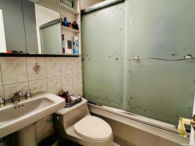 full bathroom with tasteful backsplash, sink, shower / bath combination with glass door, tile walls, and toilet