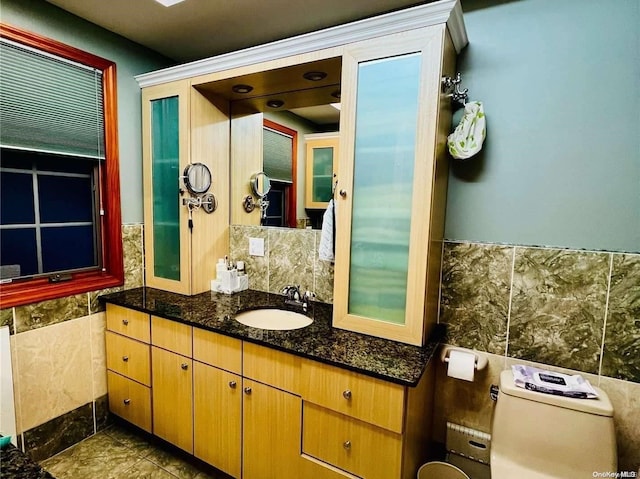 bathroom featuring vanity, toilet, and tile walls