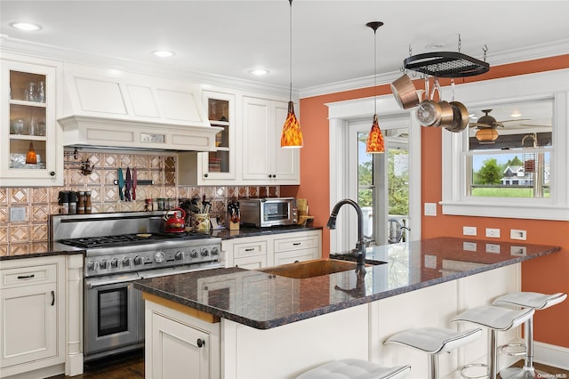 kitchen featuring backsplash, custom exhaust hood, a breakfast bar, range with two ovens, and white cabinets