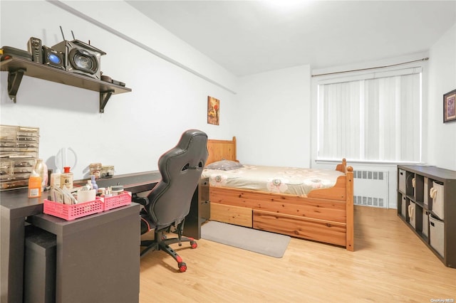 bedroom featuring radiator and light hardwood / wood-style floors