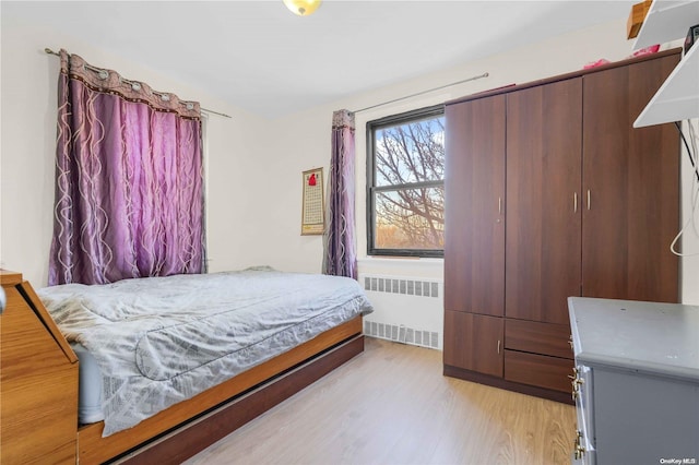 bedroom with radiator heating unit and light hardwood / wood-style floors