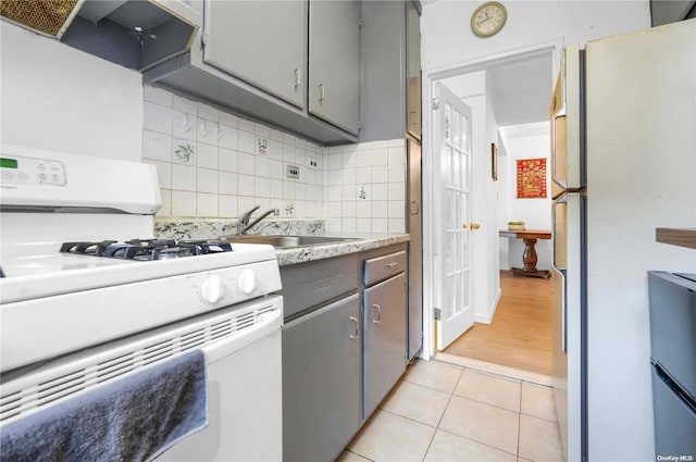 kitchen featuring white appliances, ventilation hood, sink, gray cabinets, and light tile patterned flooring