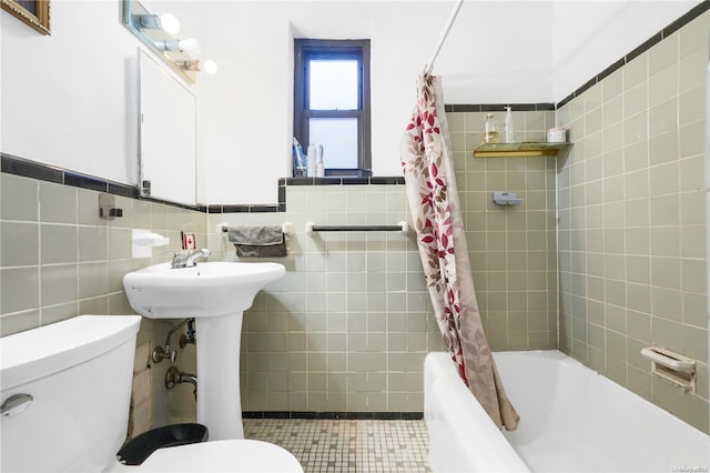 bathroom with toilet, tile walls, and shower / bath combo with shower curtain