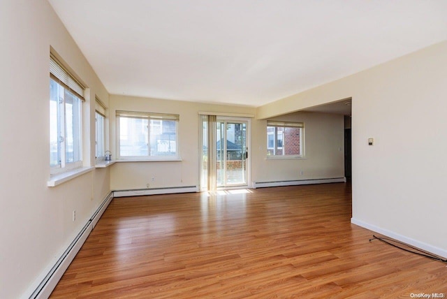 empty room featuring light hardwood / wood-style flooring, plenty of natural light, and a baseboard heating unit