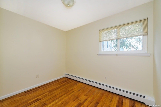 empty room featuring hardwood / wood-style floors and baseboard heating