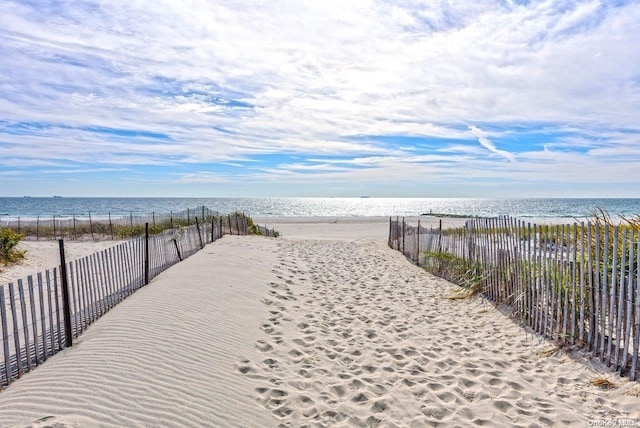 surrounding community featuring a water view and a beach view