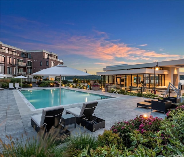 pool at dusk with a patio area