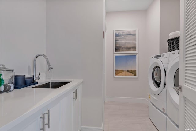 laundry area featuring cabinets, washer and clothes dryer, and sink