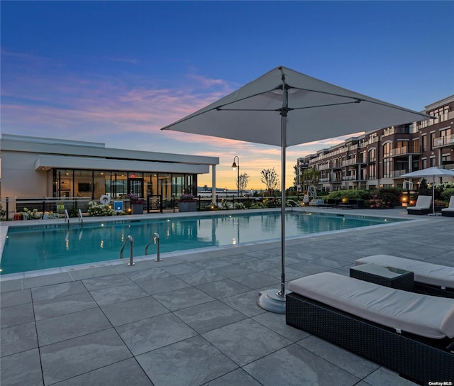 pool at dusk featuring a patio area