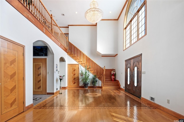 foyer featuring a high ceiling, hardwood / wood-style flooring, plenty of natural light, and ornamental molding