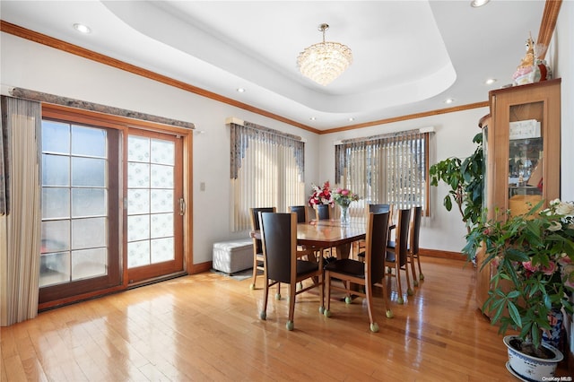 dining space with a raised ceiling, light hardwood / wood-style flooring, and crown molding