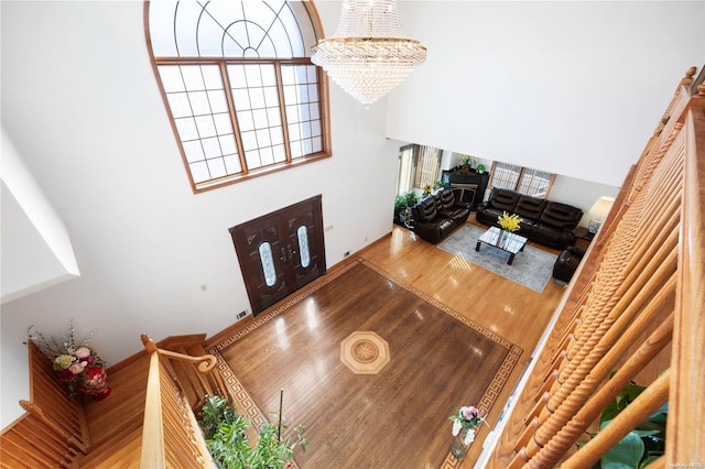 living room with a notable chandelier, wood-type flooring, and a high ceiling