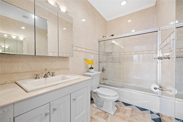 full bathroom featuring vanity, bath / shower combo with glass door, crown molding, toilet, and tile walls