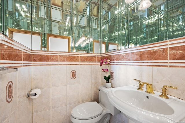 bathroom with toilet, sink, and tile walls