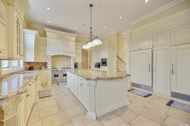 kitchen featuring a center island with sink, ornamental molding, sink, and hanging light fixtures