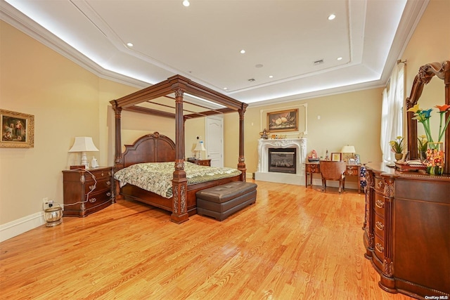 bedroom with a tray ceiling, crown molding, and light wood-type flooring