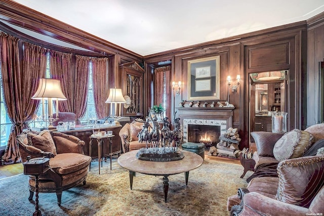 living area featuring wood walls, crown molding, and a tiled fireplace