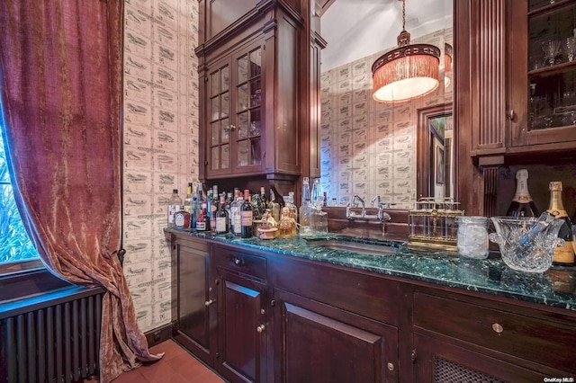 bar featuring light tile patterned floors, radiator, dark stone counters, and sink