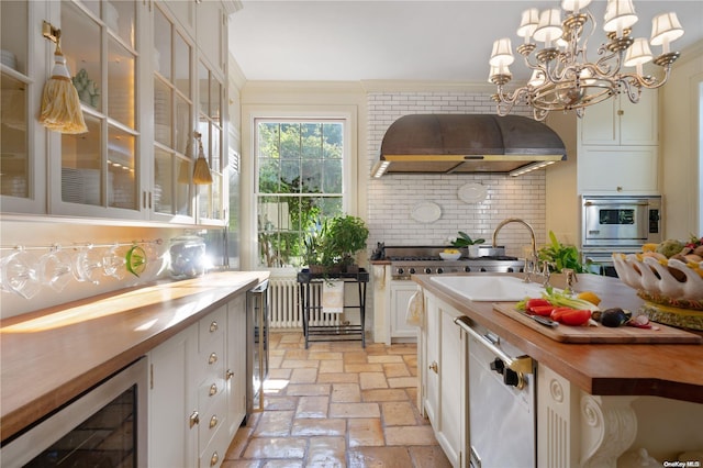 kitchen featuring wooden counters, decorative backsplash, white cabinetry, and wall chimney exhaust hood