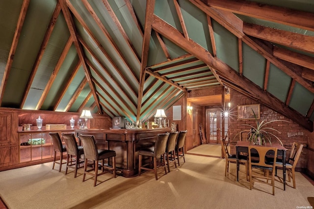 interior space featuring light carpet, lofted ceiling with beams, decorative light fixtures, and wooden walls