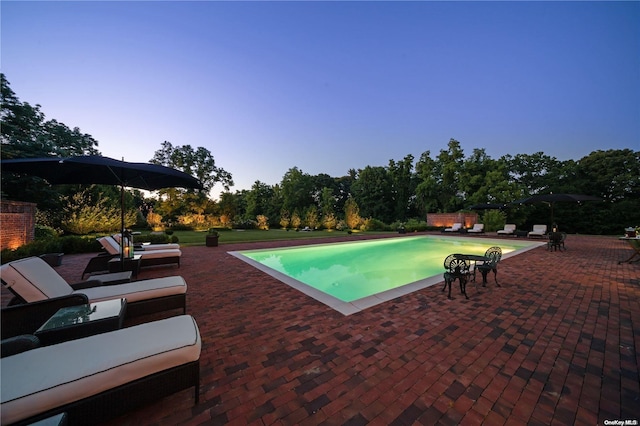 pool at dusk with a patio area