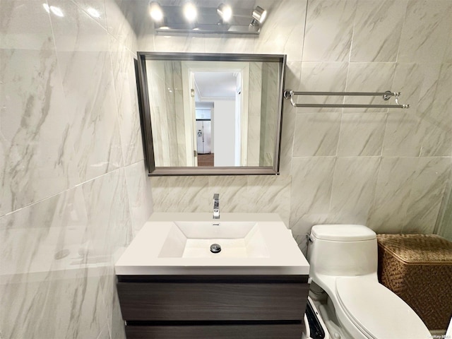 bathroom with vanity, toilet, and tile walls