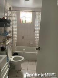 bathroom featuring tile patterned flooring, toilet, and shower / bathtub combination with curtain