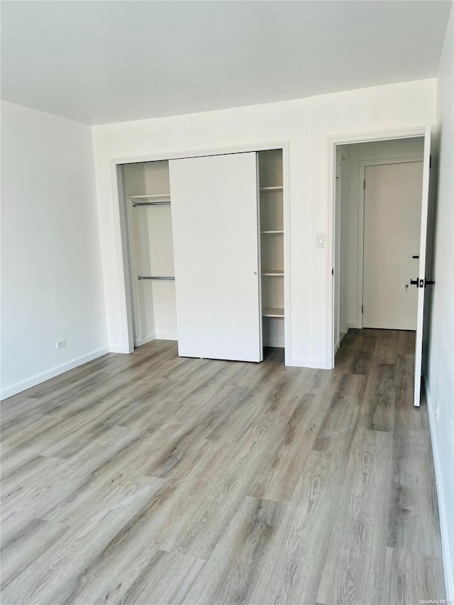 unfurnished bedroom with light hardwood / wood-style flooring and a closet