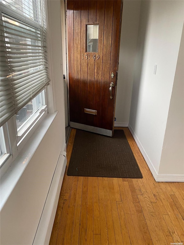 doorway to outside with light wood-style floors, baseboard heating, and baseboards