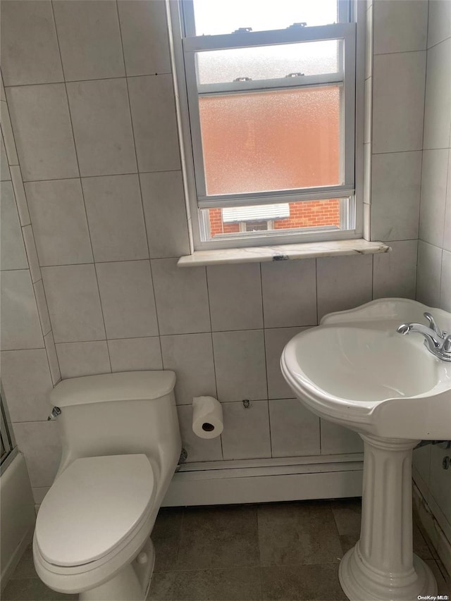 bathroom with toilet, tile patterned flooring, bath / shower combo with glass door, and tile walls