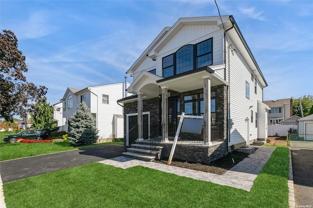 view of front of home featuring covered porch, a garage, and a front yard