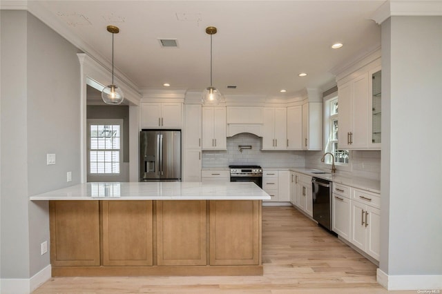 kitchen featuring white cabinetry, stainless steel appliances, kitchen peninsula, light hardwood / wood-style floors, and ornamental molding