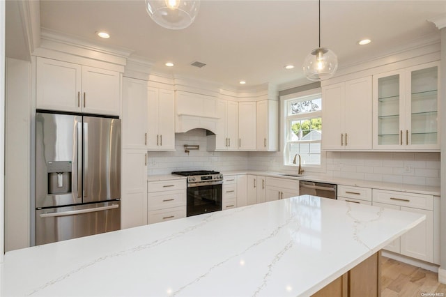 kitchen with white cabinetry, hanging light fixtures, stainless steel appliances, tasteful backsplash, and light stone counters