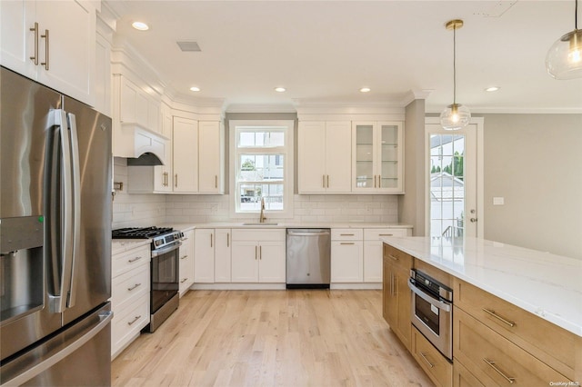 kitchen featuring pendant lighting, a healthy amount of sunlight, light stone counters, and appliances with stainless steel finishes