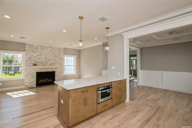 kitchen featuring oven, ornamental molding, a fireplace, decorative light fixtures, and light hardwood / wood-style floors