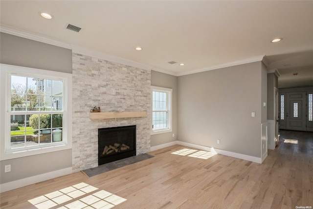 unfurnished living room featuring a fireplace, ornamental molding, light hardwood / wood-style floors, and a healthy amount of sunlight