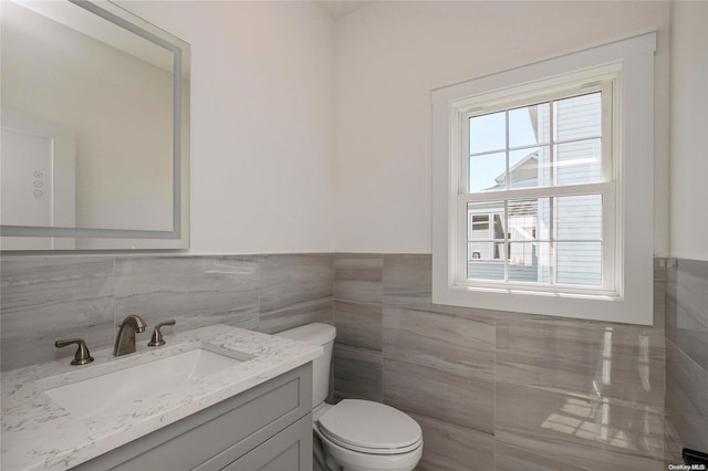 bathroom featuring vanity, toilet, and tile walls