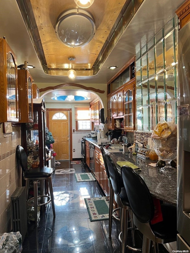 bar with black dishwasher, tile walls, radiator, and a tray ceiling