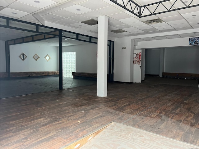 basement featuring a paneled ceiling and dark hardwood / wood-style floors