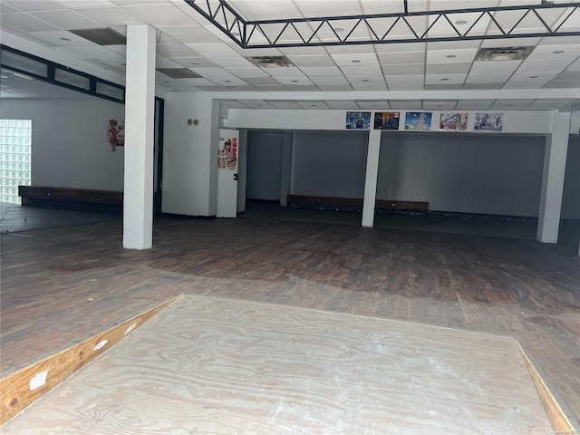 basement featuring a paneled ceiling and hardwood / wood-style floors