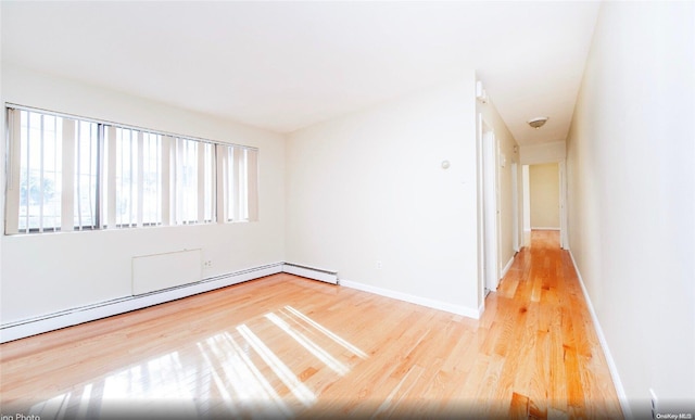 unfurnished room featuring a baseboard heating unit and light wood-type flooring